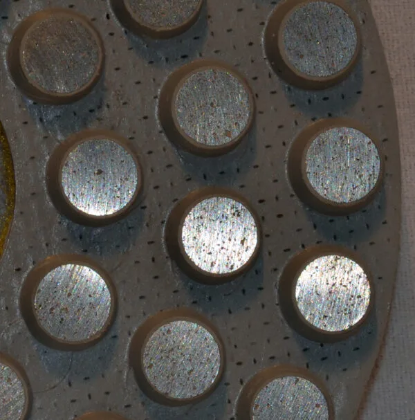 Close-up of a metallic diamond pad with dot patterns for enhanced grip.